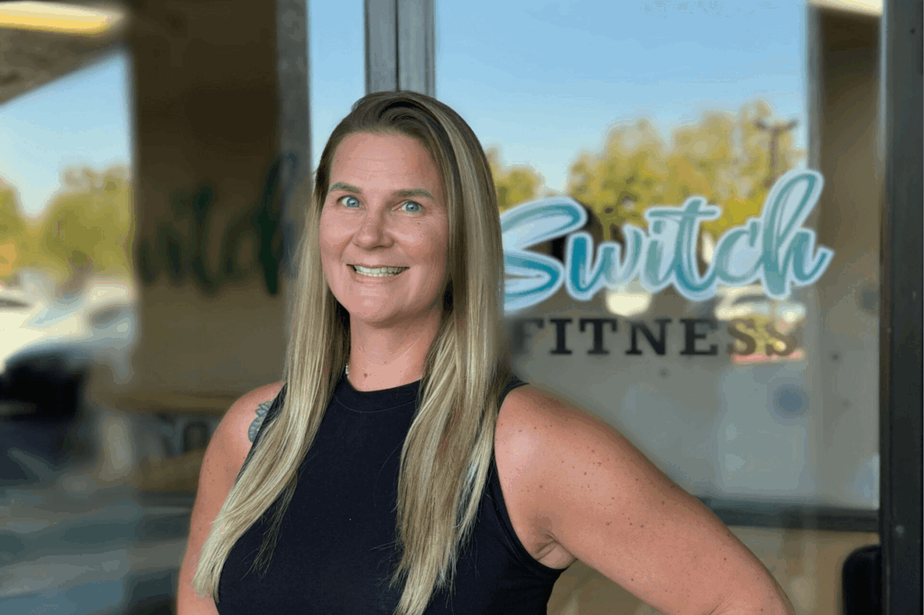 Smiling woman standing outside fitness center.