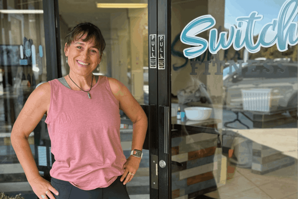 Smiling woman standing outside fitness center.